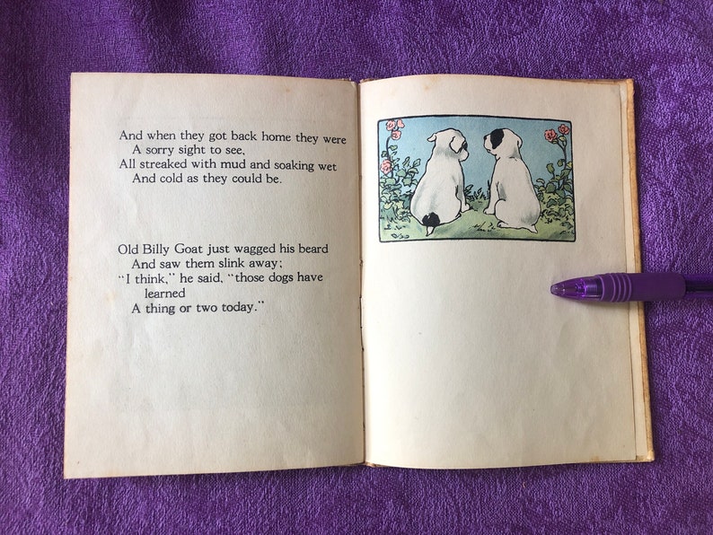 May include: Two white dogs with black spots are sitting on a green patch of grass. They are facing each other. There are pink flowers and green leaves behind them. The text on the page reads: 'And when they got back home they were A sorry sight to see, All streaked with mud and soaking wet And cold as they could be. Old Billy Goat just wagged his beard And saw them slink away; 'I think,' he said, 'those dogs have learned A thing or two today.'