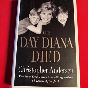 May include: A white hardcover book with a black and gold title "The Day Diana Died" by Christopher Andersen, the New York Times bestselling author of Jackie After Jack. The cover features a black and white photo of Diana, Princess of Wales, with her two sons, Prince William and Prince Harry.