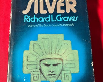 Könnte beinhalten: Ein Vintage-Taschenbuch mit dem Titel "QUICKSILVER" von Richard L. Graves. Das Cover ist dunkelblau mit silberner Schrift und einer türkisfarbenen Illustration eines stilisierten Gesichts. Das Buch befindet sich vor einem roten Hintergrund.