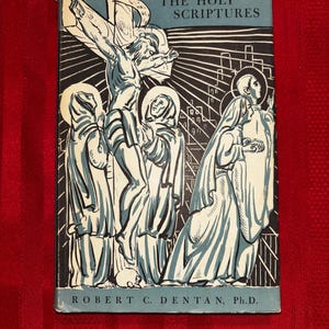 May include: A rectangular book titled The Holy Scriptures by Robert C. Dentan, Ph.D. The cover features a blue and black graphic illustration depicting a crucifixion scene with figures in robes, a cross, and a city skyline in the background.