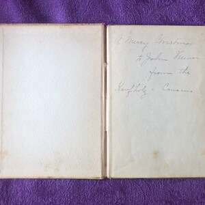 May include: A book with a white cover and a handwritten inscription on the inside cover that reads 'A Merry Christmas to John Weaver from the Family of Cousins.'