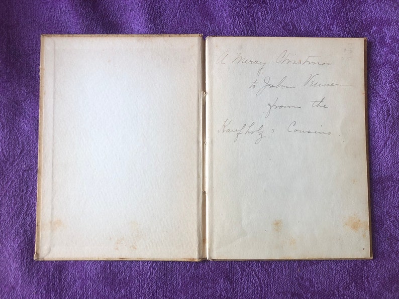 May include: A book with a white cover and a handwritten inscription on the inside cover that reads 'A Merry Christmas to John Weaver from the Family of Cousins.'