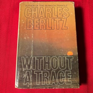 Puede incluir: Un libro de bolsillo vintage titulado "Without a Trace" de Charles Berlitz, autor de "The Bermuda Triangle". La portada presenta una puesta de sol sobre el océano.