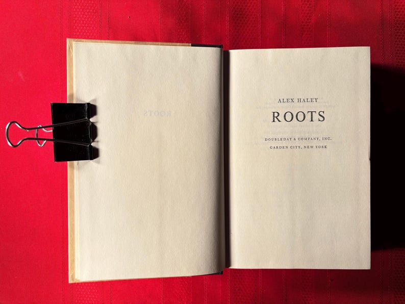May include: A close-up of the title page of the book "Roots" by Alex Haley. The book was published by Doubleday & Company, Inc. in Garden City, New York.