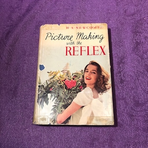 May include: A vintage book titled "Picture Making with the Reflex" by H.S. Newcomb. The cover features a woman holding a bouquet of flowers, smiling at the camera.