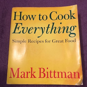 May include: A yellow cookbook with the title "How to Cook Everything" in green text and the subtitle "Simple Recipes for Great Food" in black text. The author's name, "Mark Bittman", is printed in red text at the bottom of the cover.
