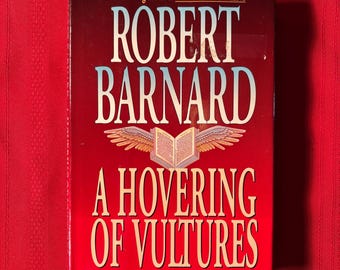 Könnte beinhalten: Ein rotes Hardcover-Buch mit dem Titel "A Hovering of Vultures" von Robert Barnard. Das Buch ist ein spannender Roman und zeigt auf dem Cover einen goldenen Adler mit ausgebreiteten Flügeln.