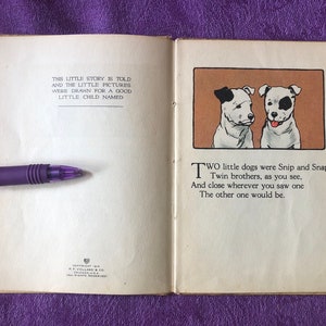 May include: An open book with a white background and black text. The book is open to a page with a picture of two white dogs with black spots. The text on the page reads: 'TWO little dogs were Snip and Snap. Twin brothers, as you see, And close wherever you saw one The other one would be.'