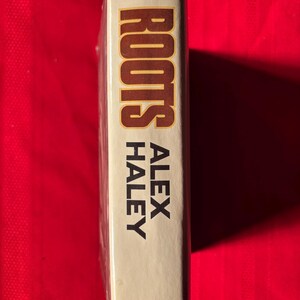 May include: A white book with the title "Roots" by Alex Haley and the publisher Doubleday printed on the spine.