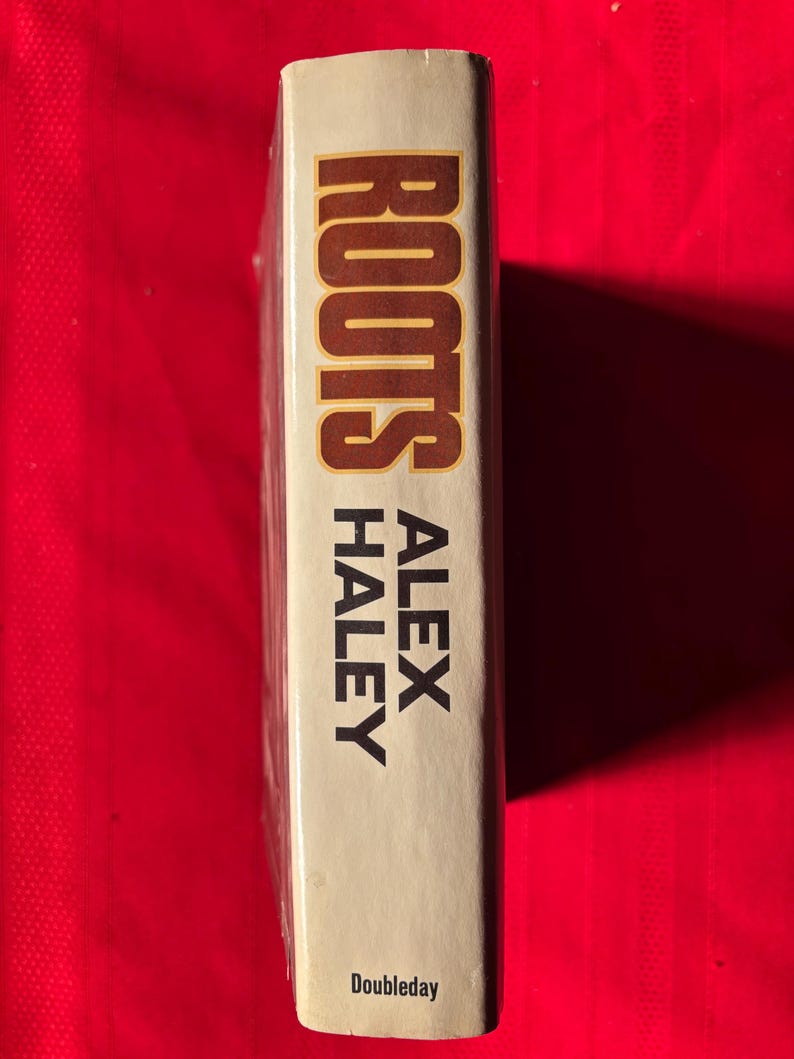 May include: A white book with the title "Roots" by Alex Haley and the publisher Doubleday printed on the spine.