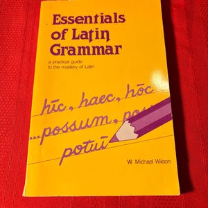 May include: A yellow book titled "Essentials of Latin Grammar" with a practical guide to the mastery of Latin. The cover features a purple pencil with handwritten Latin text: "húc, haec, hộc...possum, po potui".