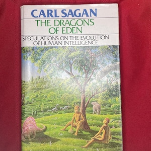 May include: A book cover with a green, yellow, and blue illustration of a prehistoric landscape with two people, a dinosaur, and a tree. The book title is "The Dragons of Eden: Speculations on the Evolution of Human Intelligence" by Carl Sagan.