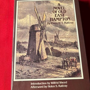 May include: A hardcover book titled "The Adventures of Jeremiah Dimon: A Novel of Old East Hampton" by Everett T. Rattray. The cover features a sepia-toned illustration of windmills, a horse-drawn cart, and figures in a rural landscape.