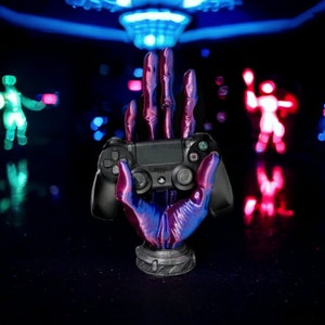 May include: A black PlayStation controller held by a purple and blue skeletal hand, with a neon blue and pink background.