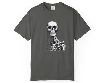 May include: Dark gray t-shirt featuring a black and white illustration of a human skeleton. The skeleton's skull and rib cage are prominently displayed, with details like dripping lines adding visual interest. The shirt has a classic crew neck and short sleeves.