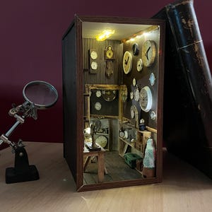 May include: A detailed miniature clock shop diorama, showcasing a variety of clocks. The interior is lit, with a magnifying glass and a large, open book. The scene is set against a dark red background. The diorama is a unique decorative item.