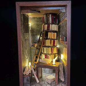 Könnte beinhalten: Miniatur-Diorama einer Bibliothek in einem Holzrahmen. Die Szene zeigt einen Stapel Bücher, eine Holzleiter, einen kleinen Tisch mit Schriftrollen und sanfte Beleuchtung. Die Wände sind aus Stein.