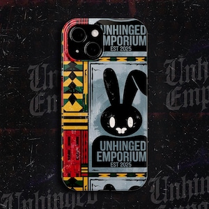 Può includere: Custodia per telefono con un motivo geometrico colorato sul lato sinistro e un design in bianco e nero sul lato destro. Il design presenta un coniglio nero e il testo "UNHINGED EMPORIUM EST 2025".