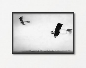 Op de afbeelding: Een zwart-witfoto van twee vliegtuigen die in de lucht vliegen. Het grotere vliegtuig is op de voorgrond en het kleinere vliegtuig is op de achtergrond.