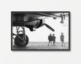 Peut inclure: Photographie en noir et blanc d'un avion vintage avec trois enfants debout devant lui. Les enfants regardent l'avion.