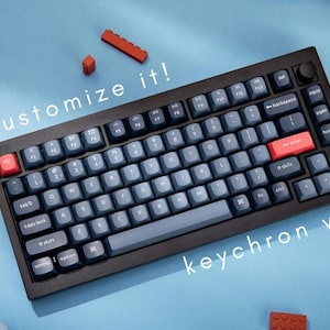 May include: A black keyboard with a grey and blue keycap set. The keyboard has a red enter key and a knob on the top right corner. The text "customize it!" and "keychron v1" are visible on the keyboard.