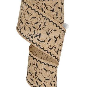 May include: A roll of decorative burlap ribbon with a scalloped edge and black embroidered floral design. The ribbon is tan with a teal and white label that reads "RG Ribbon Collection".