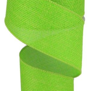 May include: A roll of bright green burlap ribbon with a textured weave. The ribbon is on a white spool.
