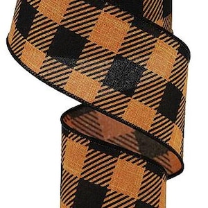 May include: A spool of wired ribbon featuring a black and orange buffalo plaid pattern. The fabric has a textured weave, and the edges are finished with a black stitched border. The ribbon is wound around a white plastic cylindrical core.