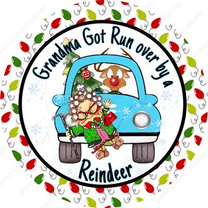 May include: A round Christmas ornament with a white background and a blue car with a woman and a reindeer inside. The text "Grandma Got Run Over By A Reindeer" is written in black around the car. The ornament is surrounded by a border of red and green Christmas lights.