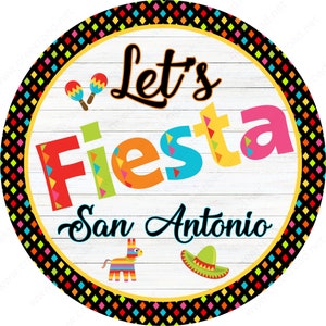 May include: A round sign with the words "Let's Fiesta San Antonio" in colorful letters. The sign features maracas, a piñata, and a sombrero. The border is a black and colorful diamond pattern on a yellow background.