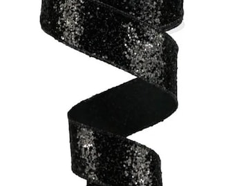 May include: A roll of black ribbon with a glittery, sequined texture. The ribbon is unwound, revealing a shiny, decorative material. The ribbon is likely used for gift wrapping, crafting, or other decorative purposes.