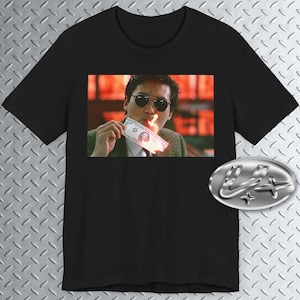 May include: Black t-shirt featuring a graphic print of a man in a suit wearing sunglasses and holding a burning dollar bill.
