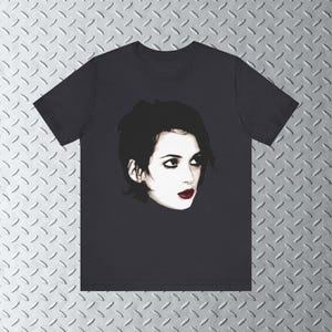 Pode incluir: Uma camiseta preta com uma estampa gr&aacute;fica de uma mulher com cabelo escuro e batom vermelho. A mulher est&aacute; olhando para a direita.
