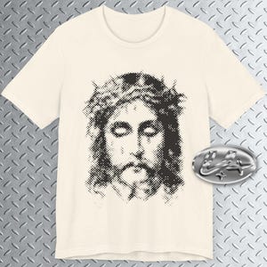 May include: A white t-shirt featuring a black and white image of a person wearing a crown of thorns. The image is pixelated and has a vintage aesthetic.