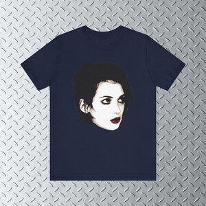 Pode incluir: Uma camiseta azul marinho com uma imagem em preto e branco de uma mulher com cabelo escuro e batom vermelho.