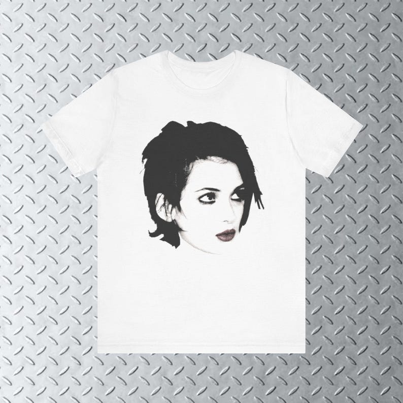 Pode incluir: Uma camiseta branca com uma imagem em preto e branco de uma mulher com cabelo curto e escuro. A mulher est&aacute; olhando para a direita da imagem.