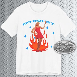 May include: White t-shirt with a graphic of a woman in a red dress standing in flames with blue raindrops falling around her. The text "NO DOUBT" is printed in blue above the graphic.