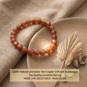 May include: An orange sunstone gemstone bracelet with a gold bead. The image shows the bracelet on a neutral surface, with dried foliage. The text reads: "100% Natural Untreated, Non-Copper Diffused Guaranteed Top Quality Sunstone (6mm) Metal: 14K SOLID GOLD- Made in USA."