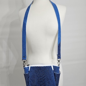 May include: A blue crossbody bag with a snake-skin pattern. The bag has a white zipper and two small pockets on the front. The strap is a matching blue and is attached with black hardware.