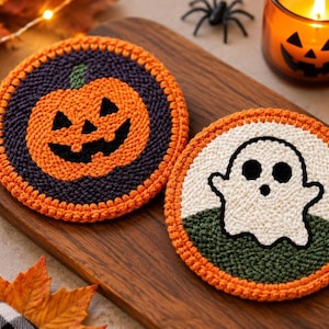 Pode incluir: Dois porta-copos circulares de crochê com designs de Halloween. Um porta-copos exibe uma abóbora laranja em um fundo roxo escuro, enquanto o outro mostra um fantasma branco em um fundo verde escuro, ambos contornados com fio laranja.