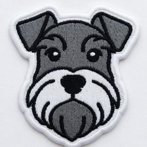May include: Embroidered patch featuring a Schnauzer dog's face. The patch has a white border, with the dog's face in shades of gray and black. The dog's eyes, nose, and mouth are clearly defined, and the patch is likely for clothing or accessories.