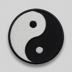 May include: A circular embroidered patch featuring a classic black and white yin yang symbol. The design consists of two interlocking teardrop shapes, one black and one white, each containing a small circular dot of the opposite color.