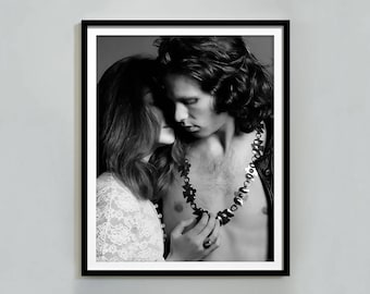 Può includere: Stampa incorniciata in bianco e nero con un uomo e una donna in un abbraccio intimo. L'uomo indossa una grande collana e una giacca di pelle. La donna indossa un top di pizzo. L'immagine è un ritratto.