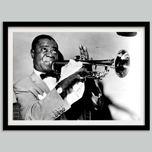 May include: A black and white photograph of a man playing a trumpet. He is wearing a suit and a bow tie. The trumpet is held in his right hand and he is looking at the camera.