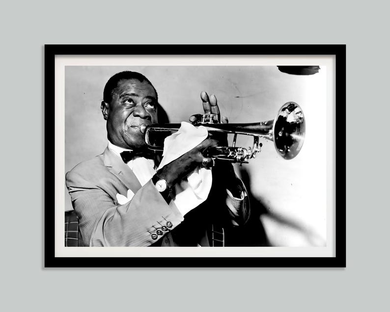 May include: A black and white photograph of a man playing a trumpet. He is wearing a suit and a bow tie. The trumpet is held in his right hand and he is looking at the camera.