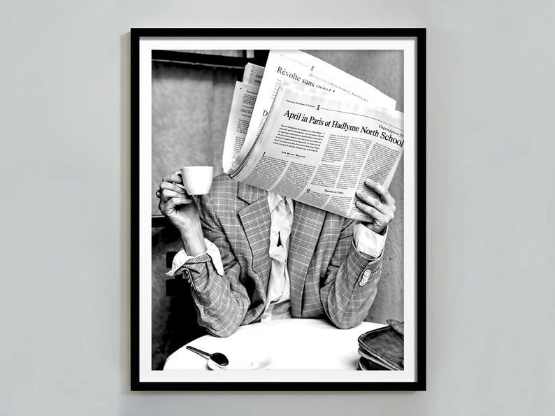 May include: A person wearing a checked blazer sits at a table, holding a cup of coffee and reading a newspaper. The newspaper headline reads "April in Paris of Hadlyme North School".