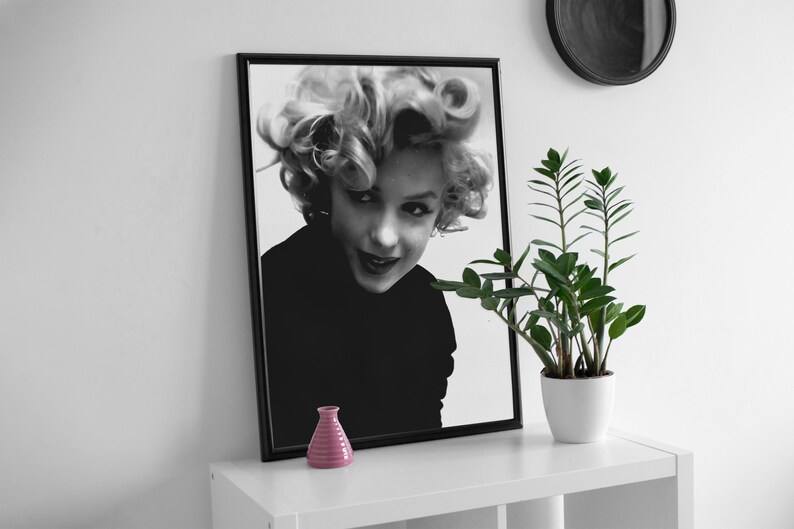 Peut inclure: Photographie en noir et blanc encadr&eacute;e d'une femme aux cheveux blonds regardant l'appareil photo. La femme porte une chemise noire et a une expression s&eacute;rieuse sur son visage.
