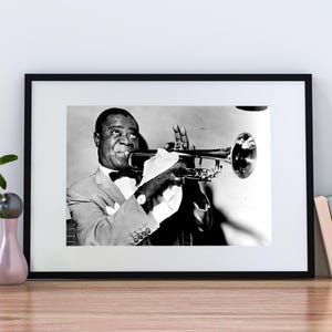 May include: Black and white photo of a man playing a trumpet. He is wearing a suit and tie and has a serious expression on his face.