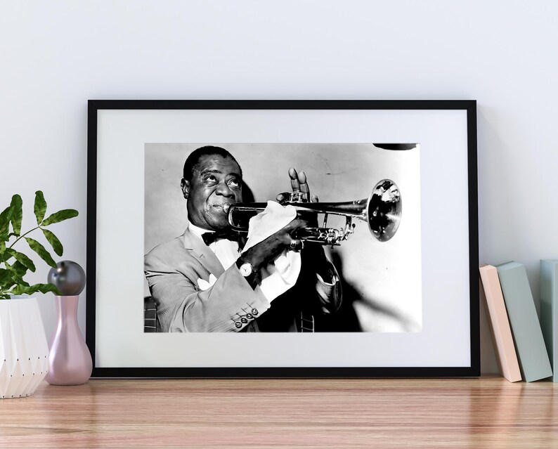 May include: Black and white photo of a man playing a trumpet. He is wearing a suit and tie and has a serious expression on his face.