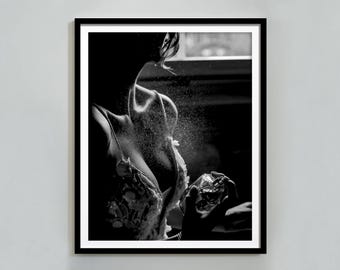 Può includere: Una fotografia in bianco e nero di una persona che spruzza profumo. La persona indossa una camicetta di pizzo e tiene una bottiglia di profumo in mano.